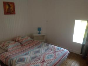 a bedroom with a bed with a quilt and a window at La Gravelle in Varaize