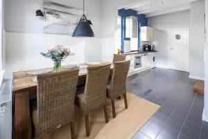 eine Küche mit einem Holztisch mit Stühlen und einer Vase aus Blumen in der Unterkunft Rothen Huus in Norderney