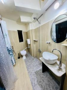 a bathroom with a sink and a toilet and a mirror at Aizawl Hotel in Āīzawl