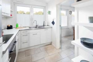 a white kitchen with a sink and two windows at Seehaus 48 in Norderney +40 photos