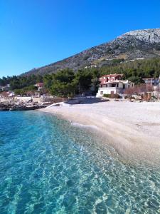 a view of a beach with a house in the background at lino in Ivan Dolac