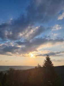 a cloudy sky with the sun setting in the distance at Haus Steindöbra in Klingenthal