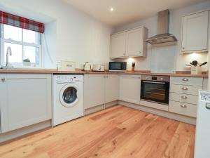 una cucina con mobili bianchi, lavatrice e asciugatrice di 1 Hull House Cottage a Skipton