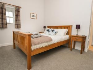 a bedroom with a wooden bed with two tables and a window at 1 Hull House Cottage in Skipton