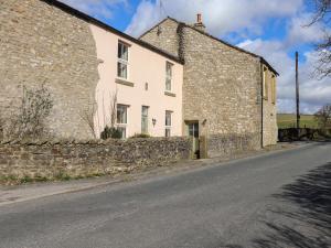 una vecchia casa in pietra sul lato di una strada di 1 Hull House Cottage a Skipton