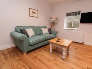 sala de estar con sofá verde y mesa en 3 Hull House Cottage, en Skipton