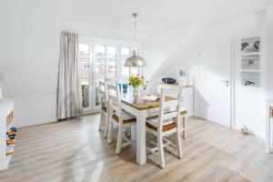 a white dining room with a white table and chairs at Strandperle Ney in Norderney