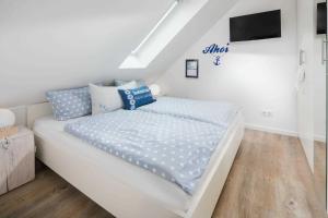 a white bed with blue pillows in a bedroom at Strandperle Ney in Norderney