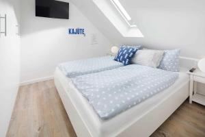 1 cama blanca con almohadas azules y blancas en una habitación en Strandperle Ney en Norderney