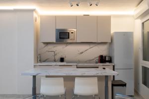 una cucina con armadi bianchi e bancone con sedie di Le Petit Prince: Appartement de haut standing a Beausoleil