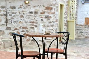 a wooden table and two chairs in front of a stone wall at Sterna Apartment in Hydra