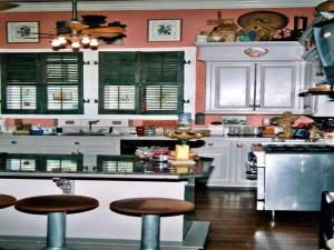 Ducote-Williams House في Abbeville: مطبخ فيه دواليب بيضاء وكراسي