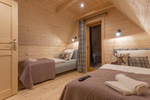 a bedroom with two beds in a wooden cabin at Domek Mietusiowa Pchełka in Poronin