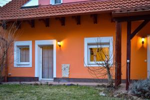 una casa de color naranja con ventanas blancas en Afrodite Apartmanház, en Eger