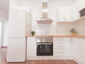 uma cozinha branca com um frigorífico e um fogão em Casa Kimo Platja em Vilanova i la Geltrú