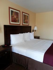 1 dormitorio con 1 cama grande con sábanas blancas en Americas Best Value Inn Bryant, en Bryant
