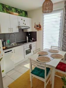 a kitchen with white cabinets and a table and chairs at Lodge Du Petit Lion proche DISNEYLAND PARIS in Montévrain