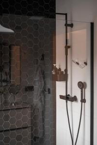ein Bad mit einer Dusche mit schwarzen Fliesen in der Unterkunft B&B De Klaproos in Merkem