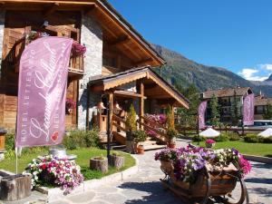 a building with a sign and flowers in front of it at Hotel Letterario Locanda Collomb in La Thuile