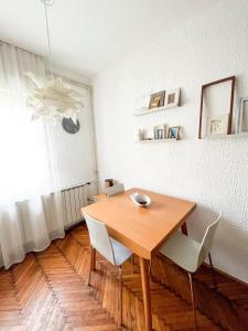 a dining room with a wooden table and white chairs at Kopernik - parking available in Belgrade