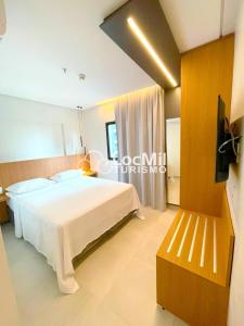 um quarto com uma grande cama branca e uma televisão em Apartamento em Resort - Premium em Salinópolis