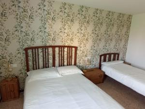 two beds in a room with floral wallpaper at Cal Pigat in Miravet