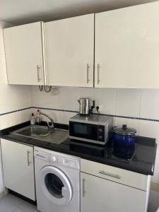a kitchen with a microwave and a washing machine at Casa Ucraniana Wi-Fi fibra in Costa Calma