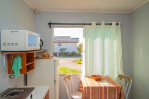 uma cozinha com um micro-ondas, uma mesa e uma janela em Cabañas Villa Los Platanos em La Serena
