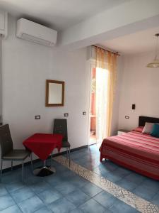 een slaapkamer met een rood bed en een tafel en stoelen bij Villa Caribe affittacamere in Monterosso al Mare