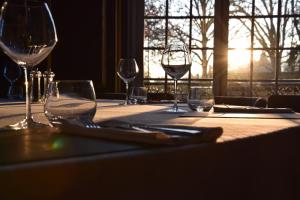 einen Tisch mit Gläsern Wein auf einem Tisch mit Fenster in der Unterkunft Hotel Ô Château in Hayange
