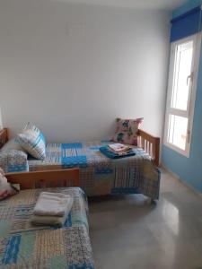 een kamer met 3 bedden en een raam bij Apartamento El Toyo in Almería