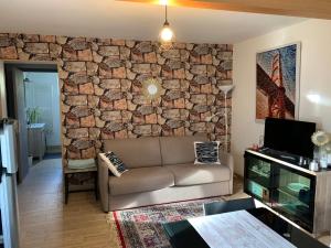 a living room with a couch and a stone wall at Studio indépendant Lisieux in Lisieux
