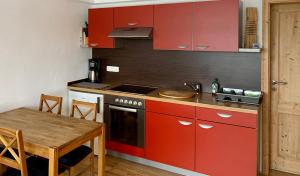 uma cozinha com armários vermelhos e uma mesa de madeira em Ferienwohnung Familie Becher Klingenthal Aschberg em Klingenthal
