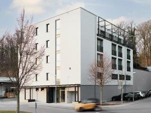 une voiture passe devant un bâtiment blanc dans une rue dans l'établissement livisit bergapartments, à Stuttgart