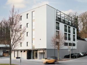 a car drives past a white building on a street at livisit bergapartments in Stuttgart
