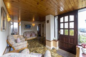 a living room with couches and a wooden ceiling at East Kelt Farm Cottage in Denny