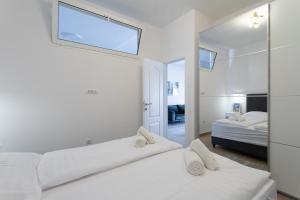 een witte slaapkamer met een bed en een spiegel bij Apartment Laura Omiš in Omiš