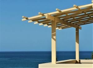 a wooden pergola with the ocean in the background at Villiana Holiday Apartments in Stalida