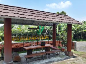 um abrigo de piquenique com uma mesa e um banco em OYO Homes 91083 Desa Wisata Plosokuning Syariah em Soprayan
