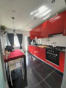 a kitchen with red cabinets and a table and a stove at Vasco da Gama Apartamento T2 com terraço PRAIA DA BARRA in Gafanha da Nazaré