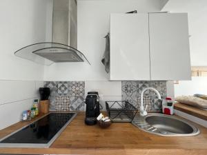 una cocina con armarios blancos y fregadero en Studio proche de la plage de l'almanarre en Hyères