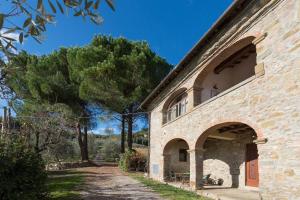 uma vista exterior de um edifício de pedra com árvores em Lake Apartment in Villa Massi em Poggio Alla Croce