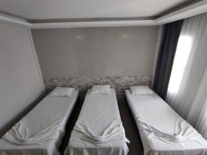 2 camas en una habitación pequeña con ventana en 1989 hotel sebat, en Cesme