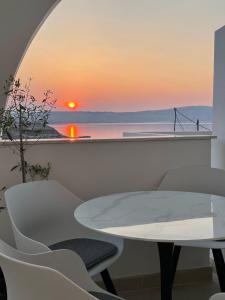 uma mesa e cadeiras com um pôr-do-sol ao fundo em Apartment Vila ** em Stinica