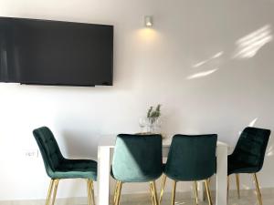 a table with four chairs and a tv on a wall at Apartment Vila ** in Stinica
