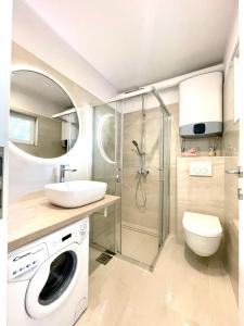 een badkamer met een wastafel en een wasmachine bij Apartment Vila ** in Stinica