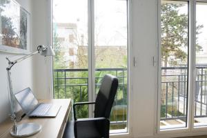 oficina con escritorio, ordenador portátil y ventana en EXIGEHOME-Appartement de standing en plein centre ville, en Maisons-Laffitte