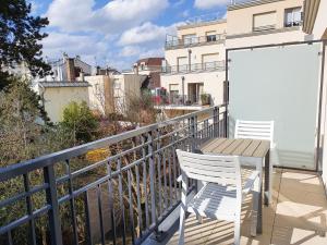 a balcony with a table and chairs on a balcony at EXIGEHOME-Appartement de standing en plein centre ville in Maisons-Laffitte