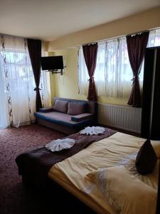 ein Hotelzimmer mit einem großen Bett und einem Sofa in der Unterkunft Belvedere Olanesti in Băile Olăneşti