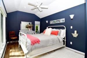 1 dormitorio azul con cama blanca y ventilador de techo en Cottage at Millpond Falls - A Romantic Escape en Warwick